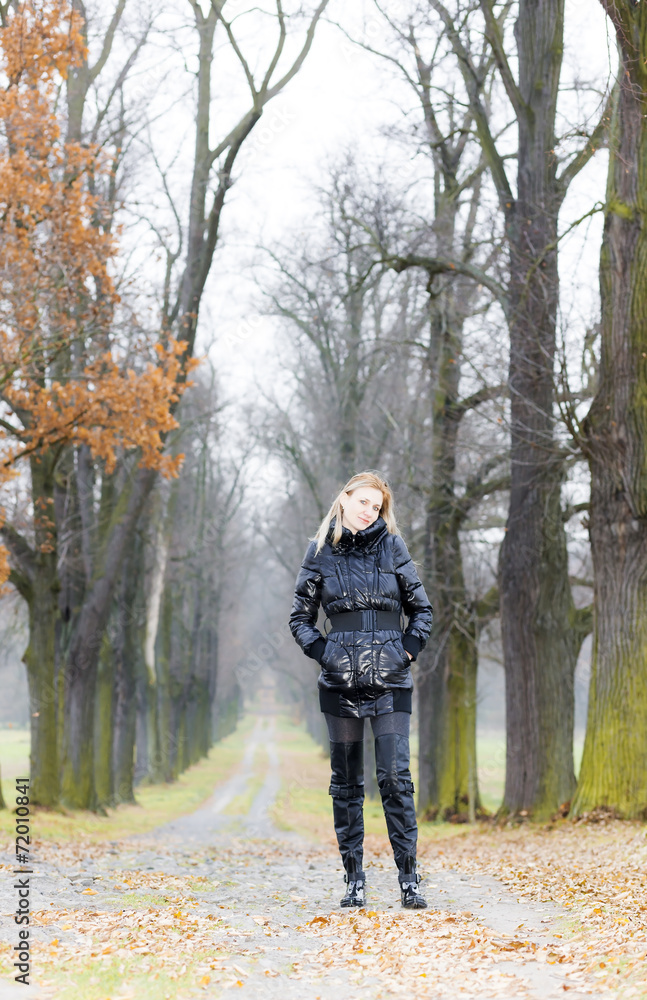 woman wearing black clothes and boots in autumnal alley woman wearing black clothes and boots in autumnal alley