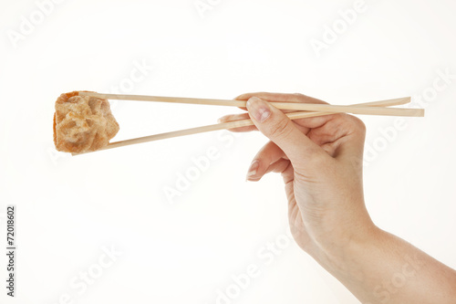 Hand holding chinese Wonton dumpling with chopsticks