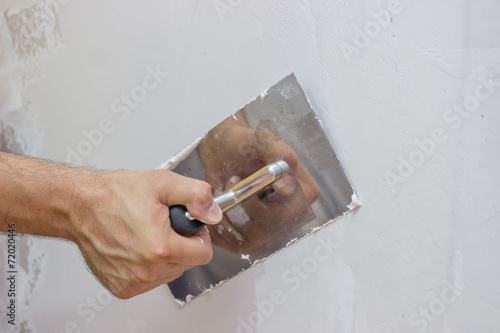 man hand with trowel plastering a wall