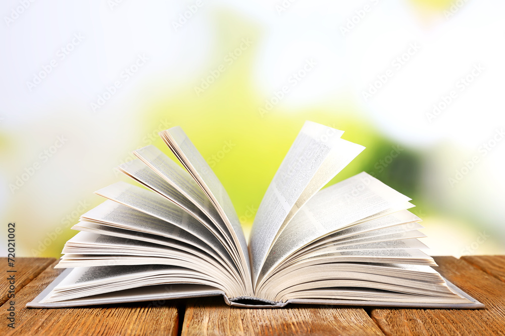 Open book on wooden table on natural background Open book on wooden table on natural background