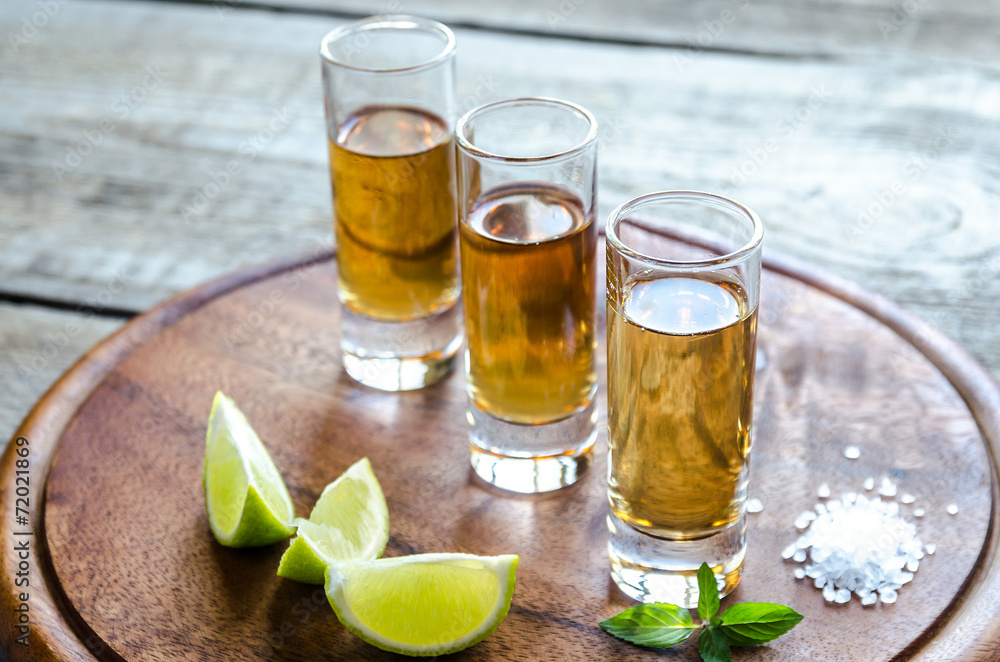 Glasses of tequila on the wooden board Glasses of tequila on the wooden board