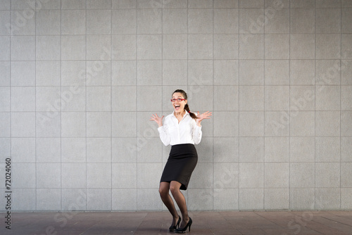 Portrait of a young business woman excited on a gray background