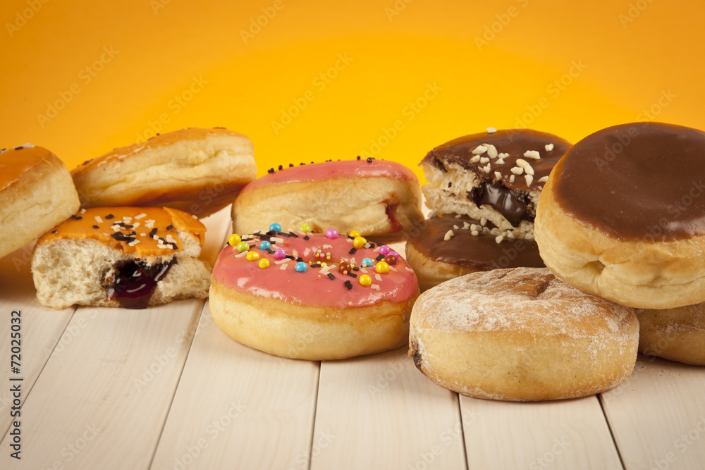 Colorful fresh doughnuts on yellow background