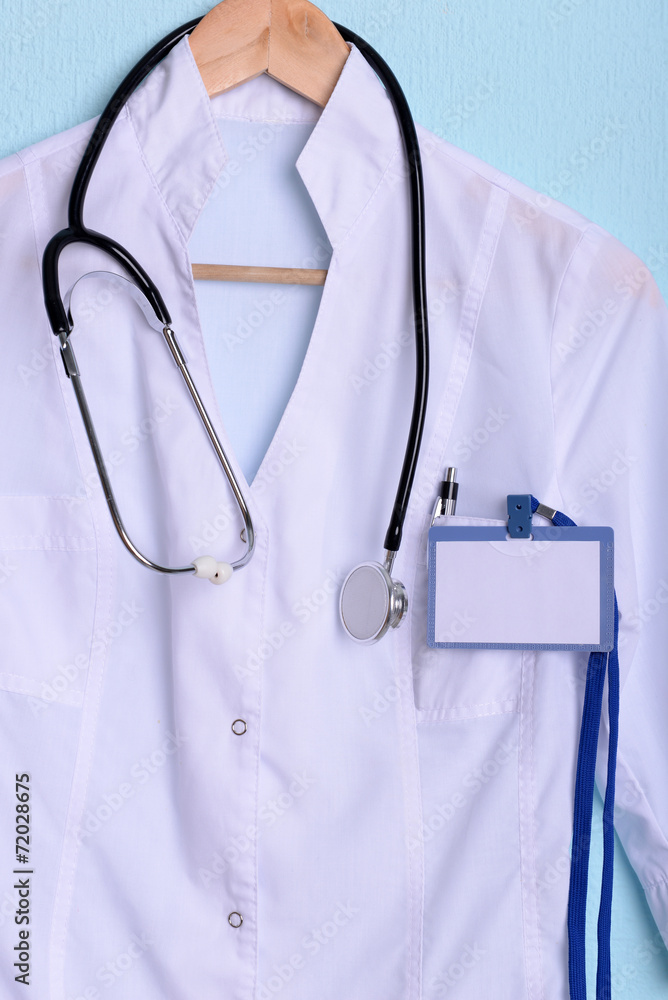 Doctor coat with stethoscope on hanger on blue background Doctor coat with stethoscope on hanger on blue background