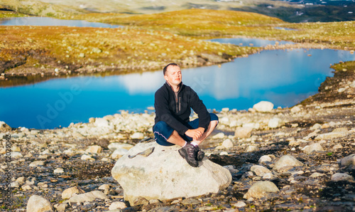 Man Sitting On Stone In Norwegian Mountains