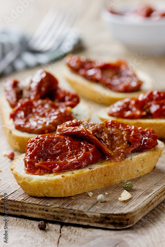 Sun-dried tomatoes and fresh bread on a wooden kitchen board
