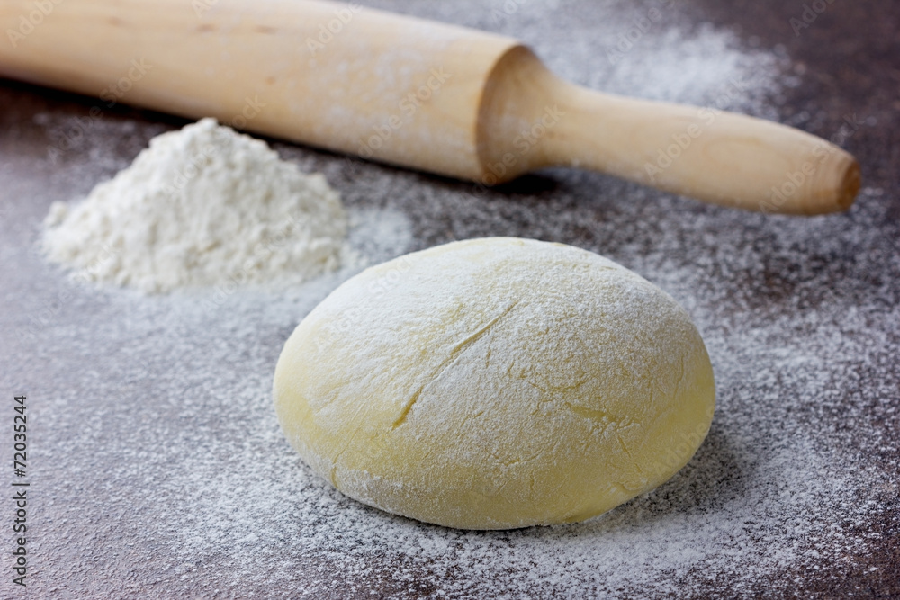 Dough with rolling pin and flour on a stone surface Dough with rolling pin and flour on a stone surface