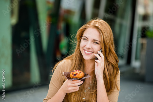 Teenager eating muffin looking in phone