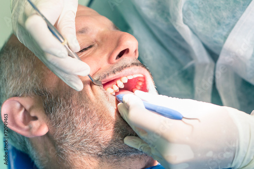 Male patient suffering during dental hygiene at dentist office -