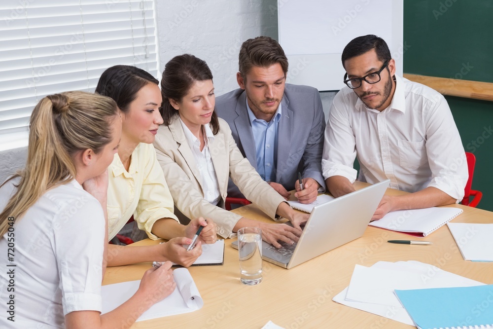 Focused business team having a meeting using laptop Focused business team having a meeting using laptop