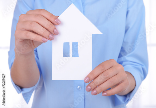 Woman hands holding paper house on light background