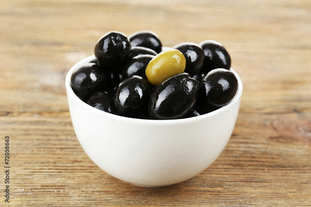 Individuality concept. Olive in bowl on wooden table Individuality concept. Olive in bowl on wooden table