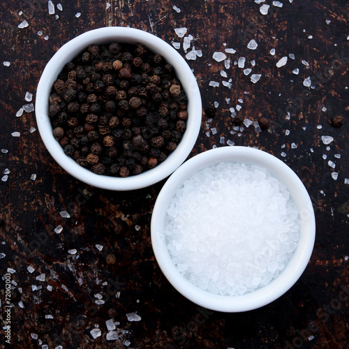 Coarse salt and black peppercorns in white ceramic bowls