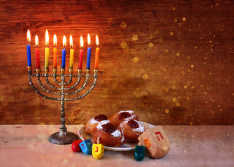 jewish holiday Hanukkah with menorah, doughnuts and wooden dreid