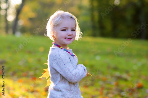 Happy little girl playing in autumn park
