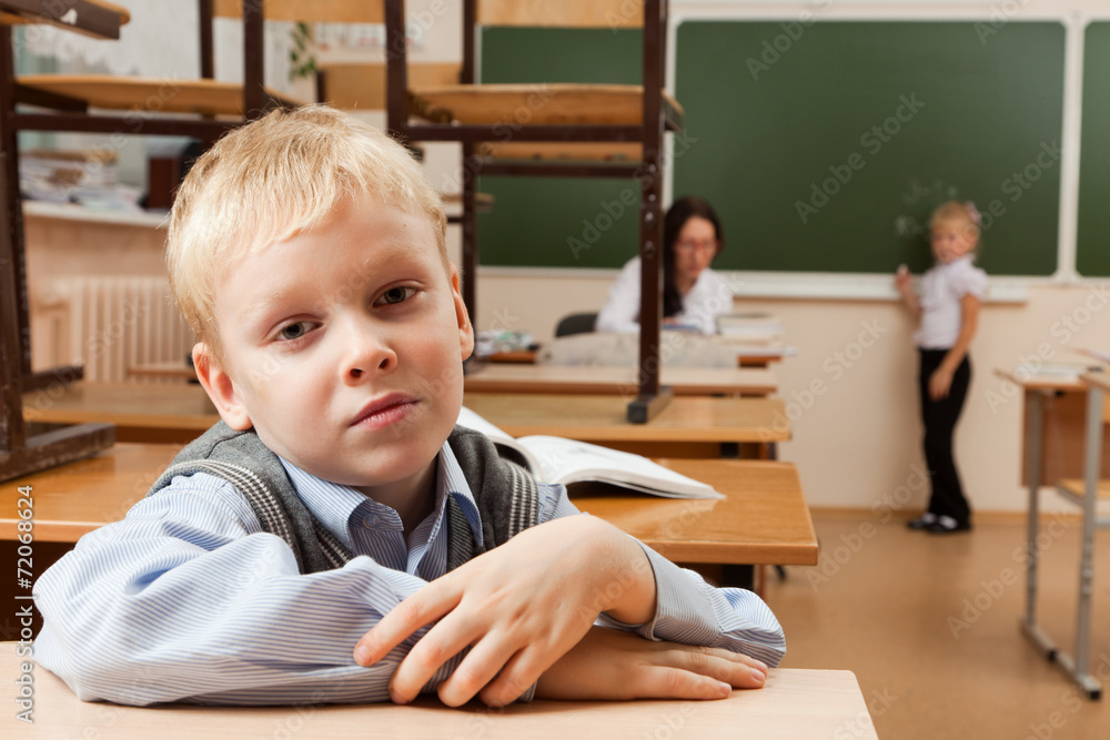 Sad schoolboy in classroom