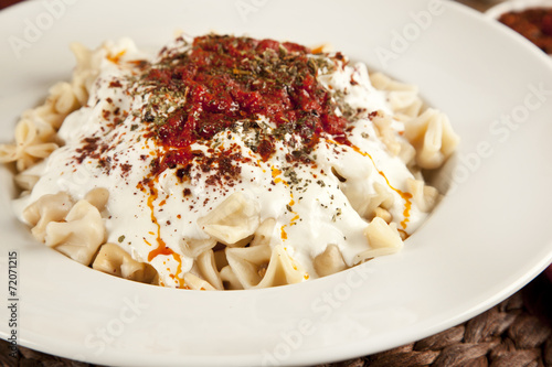 Turkish Manti manlama on plate with tomatoes sauce, yogurt photo