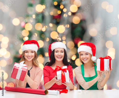 smiling women in santa helper hats packing gifts