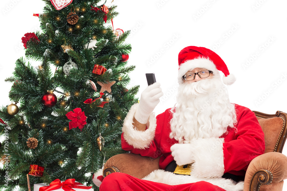 santa claus with smartphone and christmas tree