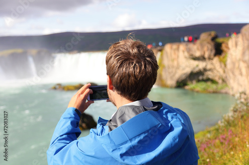 Tourist taking photo of waterfall Godafoss Iceland