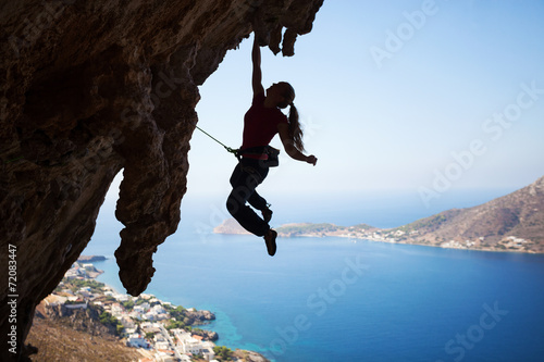 Silhouette of a young female rock climber on a cliff