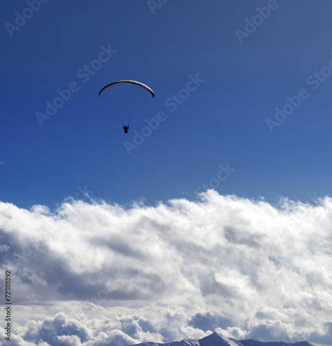 Silhouette of paraglider and blue sun sky