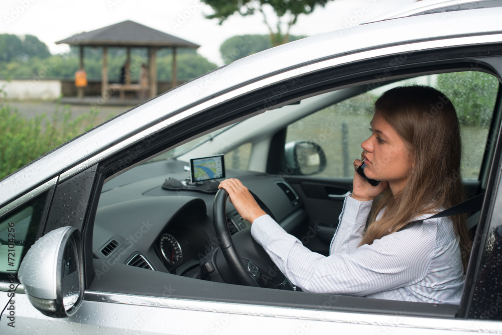 Young business woman driving car and talking on mobile phone