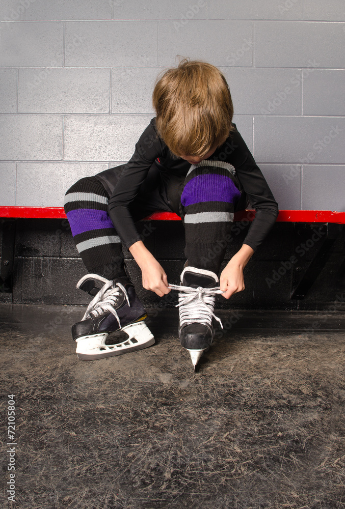 Obraz premium Boy Tying Hockey Skates in Dressing Room