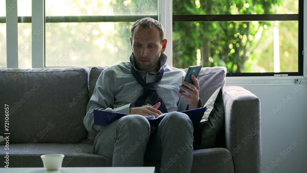 Businessman working on papers and using cellphone at home Businessman working on papers and using cellphone at home