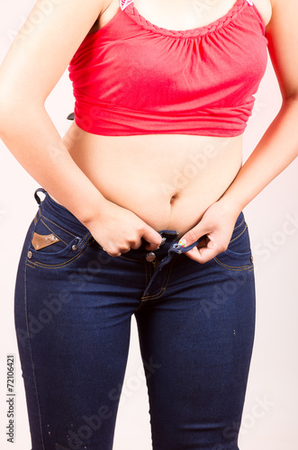 young girl struggling trying to fit into tight jeans © Fotos 593