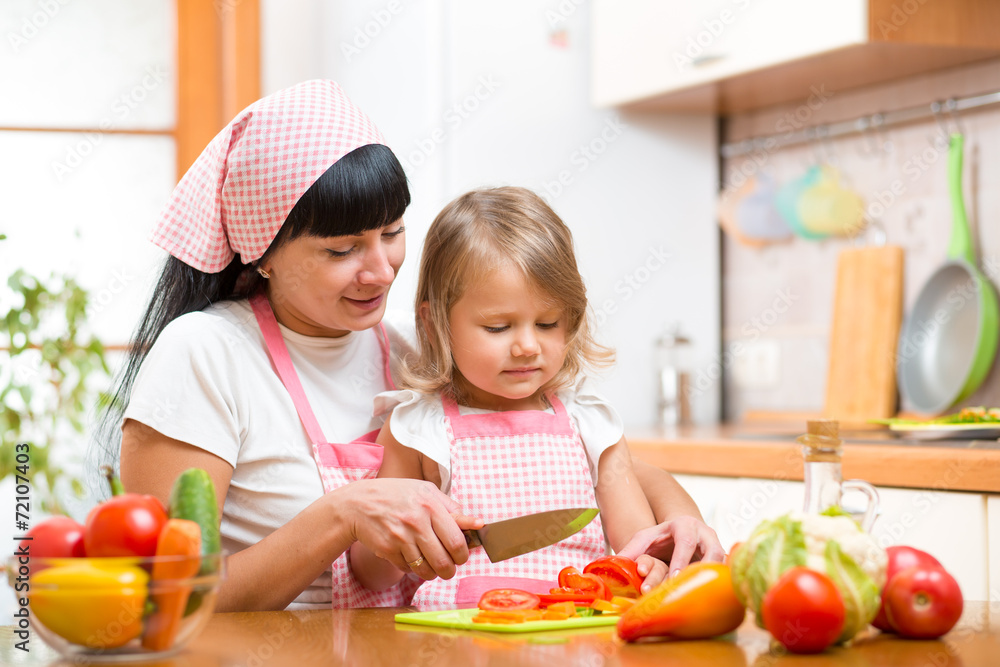 mother and kid girl cook and cut vegetables on kitchen