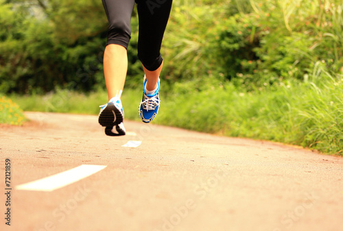  young fitness woman legs running at forest trail 