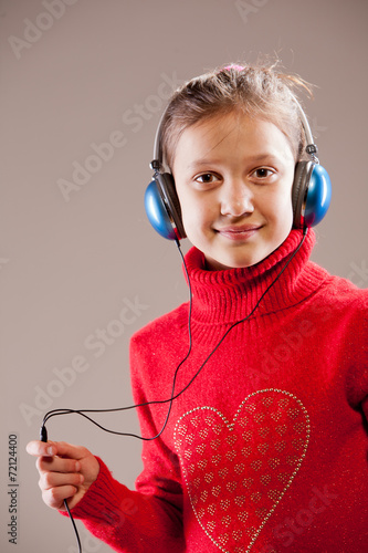 Little girl listening to the music inher blue headphones photo