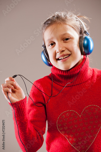 Little girl listening to the music inher blue headphones photo