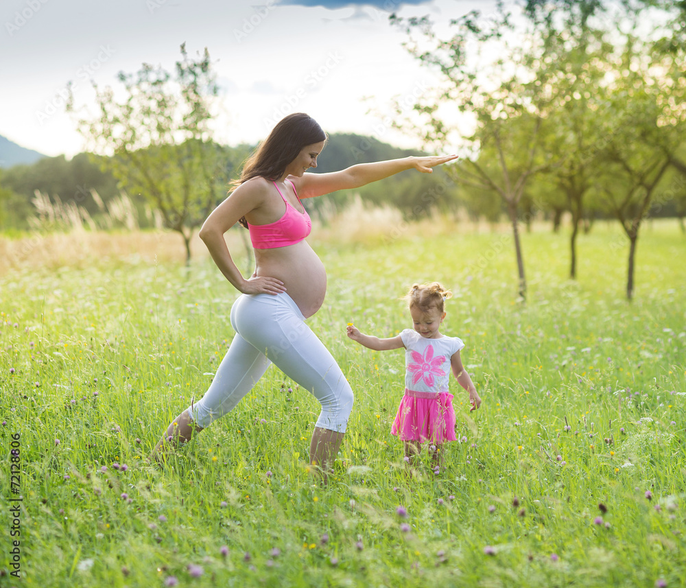 Pregnant mother with her daughter exercising Pregnant mother with her daughter exercising