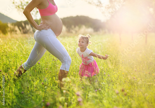 Pregnant mother with her daughter exercising