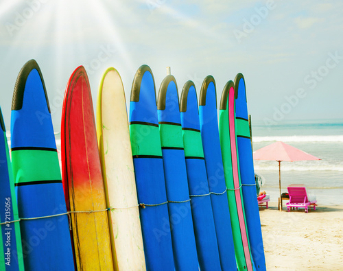 Color surf boards in a stack by ocean