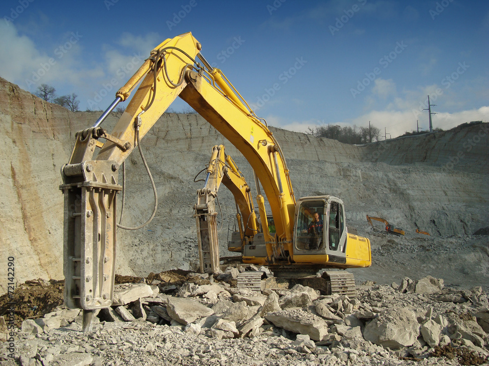 Photo of machines with a hydraulic hammer extracting rubble at the quarry Photo of machines with a hydraulic hammer extracting rubble at the quarry