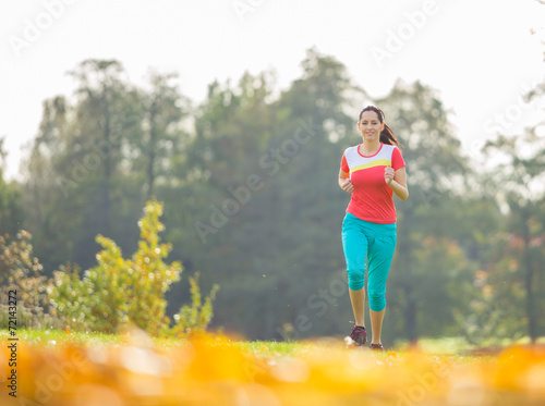 Young brunette woman running in park. © Lukas Gojda