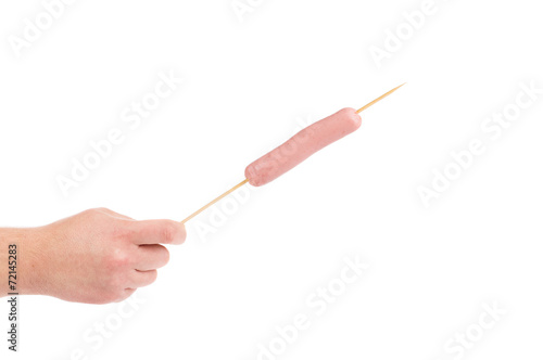 Hand holds sausage on stick