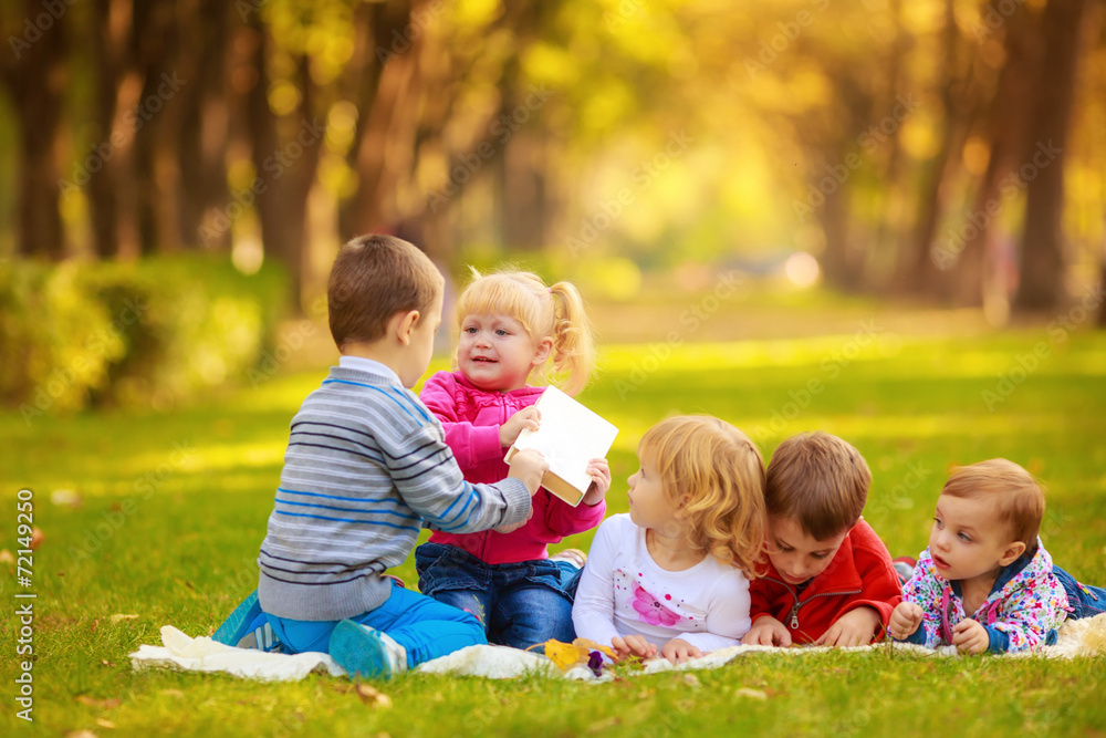 children in nature. reading a book outdoors lying on the grass children in nature. reading a book outdoors lying on the grass