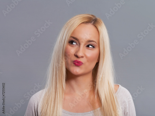 Young woman making silly face while thinking.