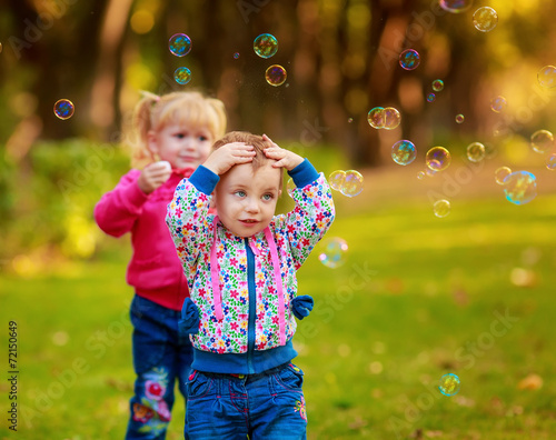 Happy kids with soap bubbles in the park. fun emotions