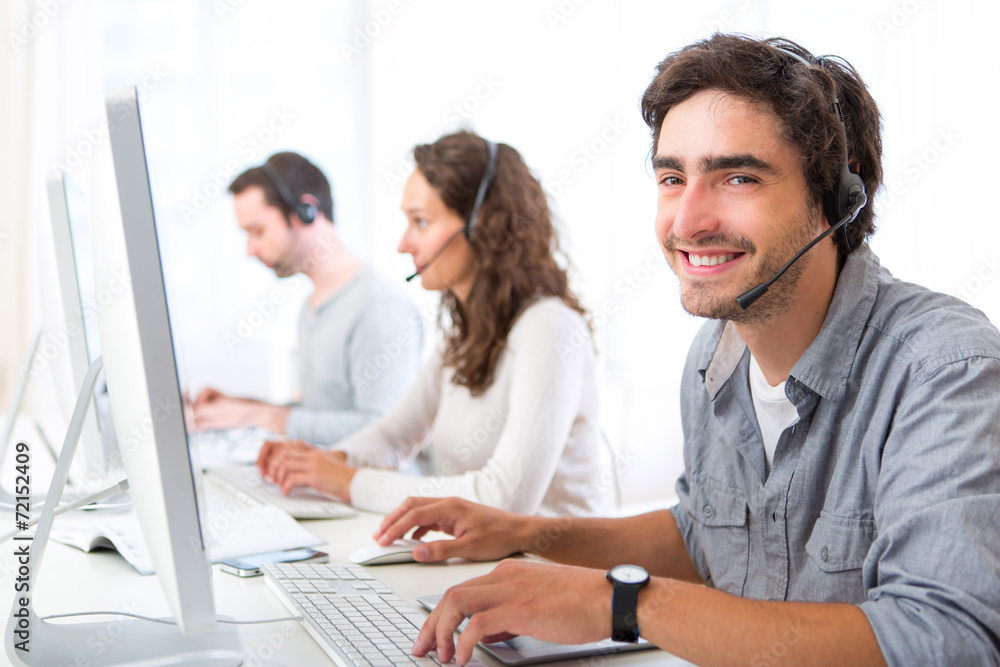 Obraz premium Young attractive man working in a call center