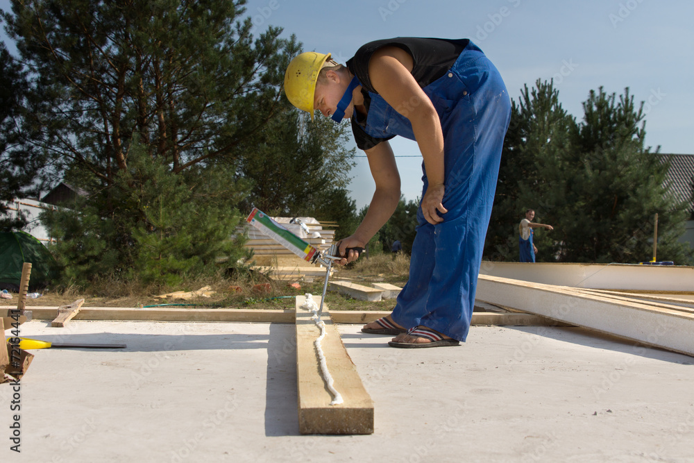 Builder applying glue to a wood beam