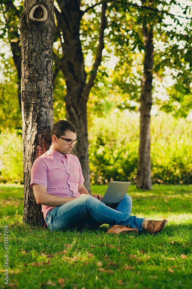 Young man sitting with Laptop Computer in the park Young man sitting with Laptop Computer in the park