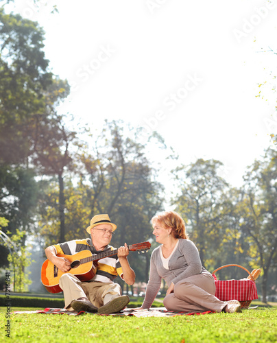 Senior playing guitar to his wife in park