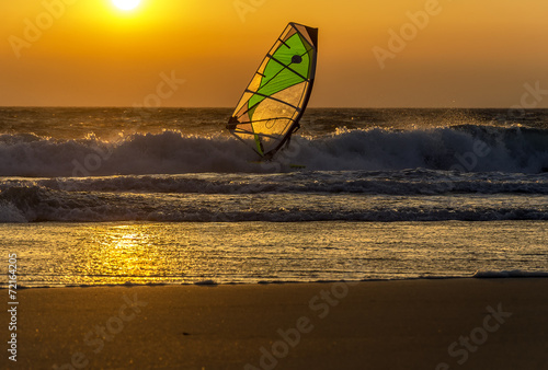 Windsurfer speeding fast against the sunset in soft focus. Summe