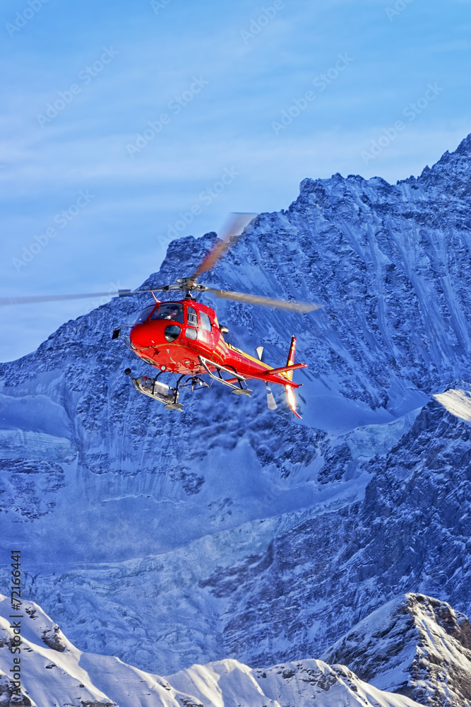Naklejka premium Red helicopter in swiss alps in winter sunshine