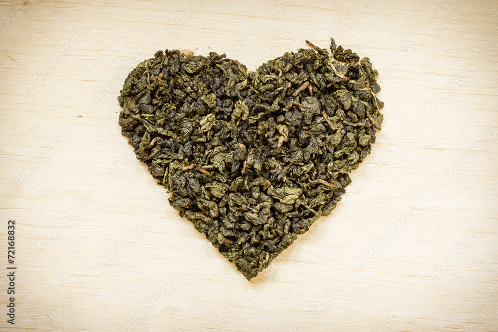 Green tea leaves heart shaped on wooden surface